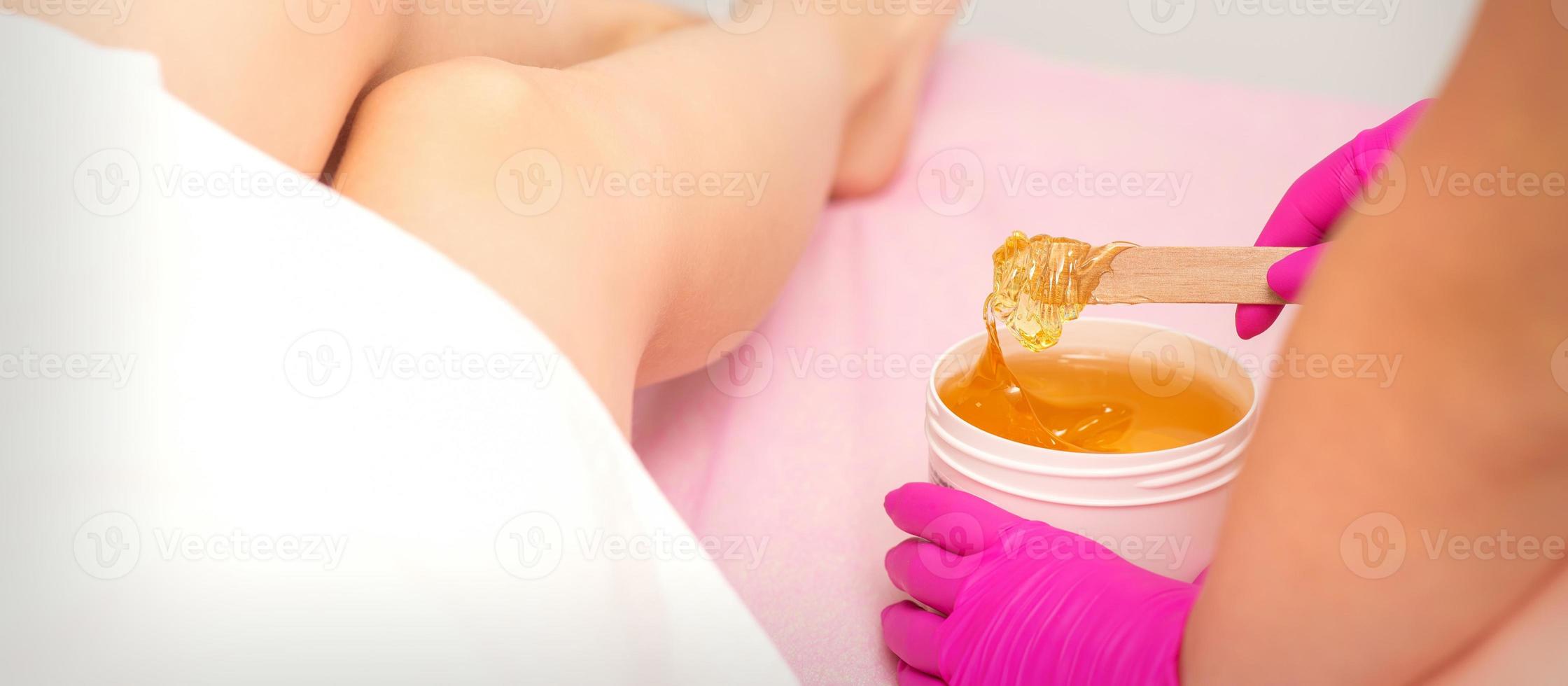 Cosmetologists waxing the female legs photo