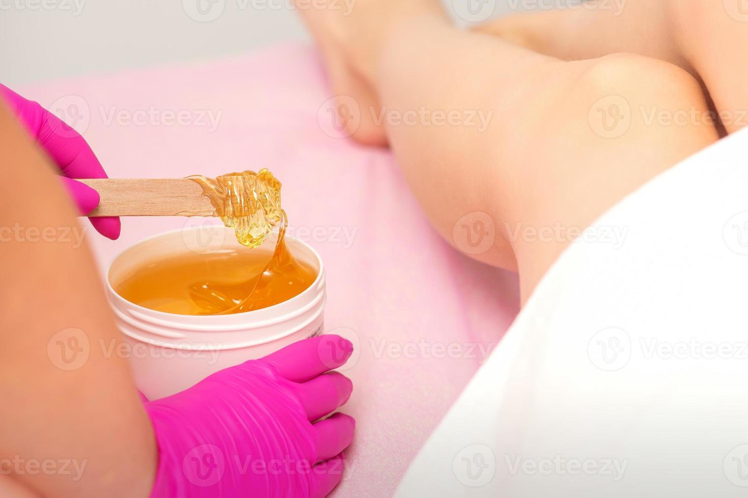 Cosmetologists waxing the female legs photo