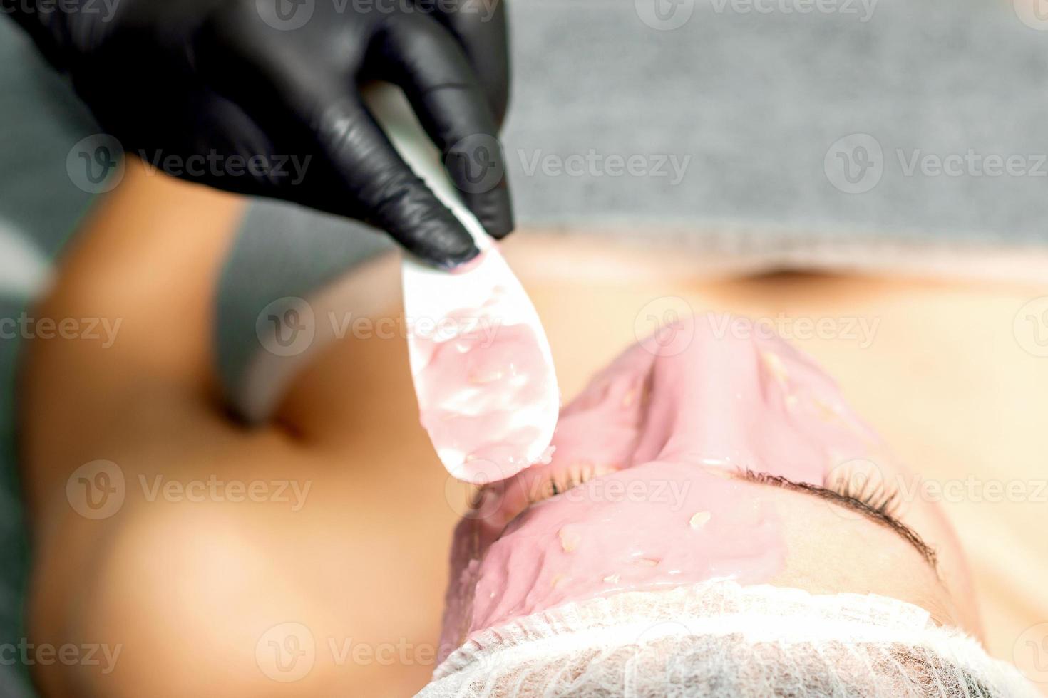 Cosmetologist applying an alginic mask photo