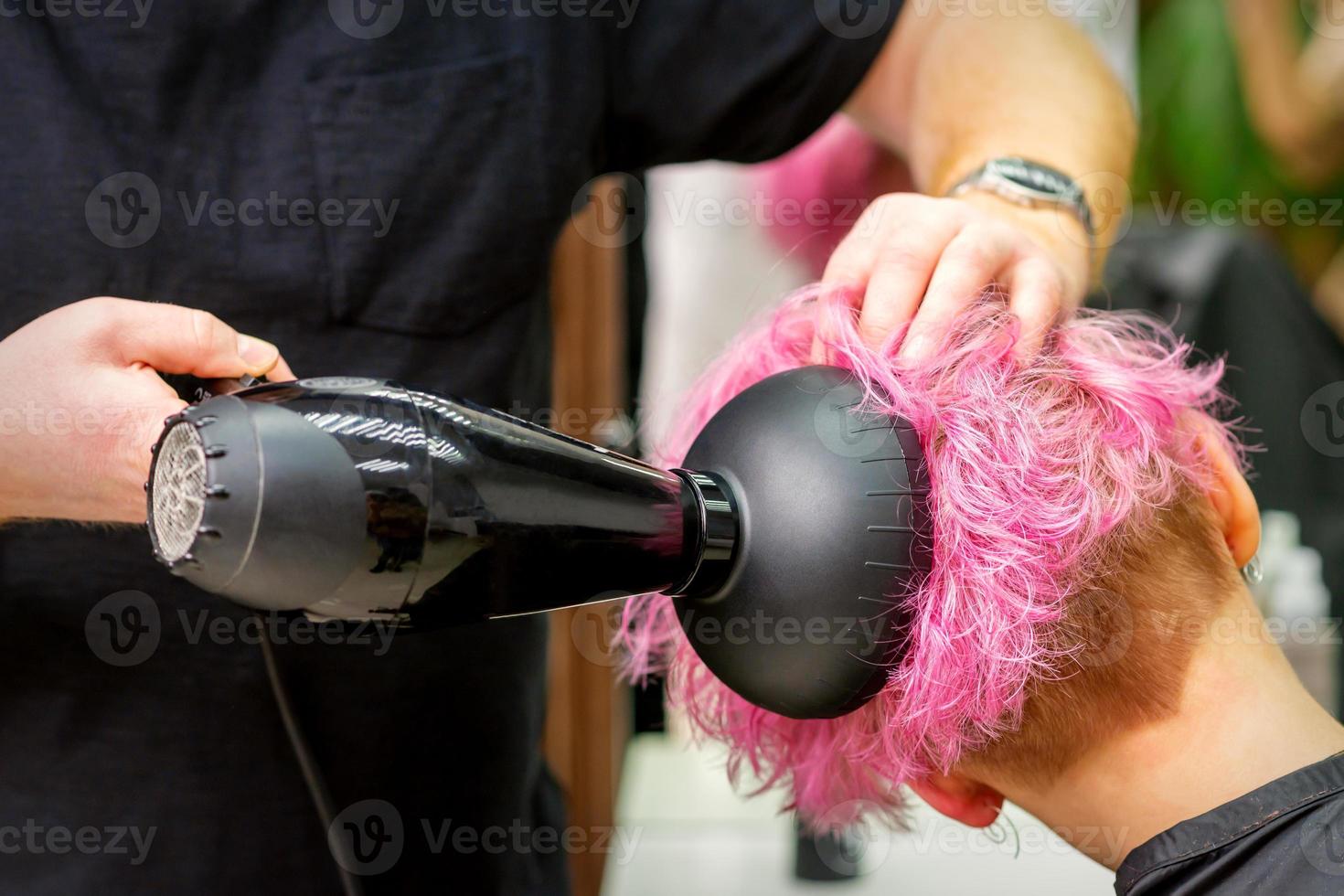 Hairdresser drying pink hair of client photo