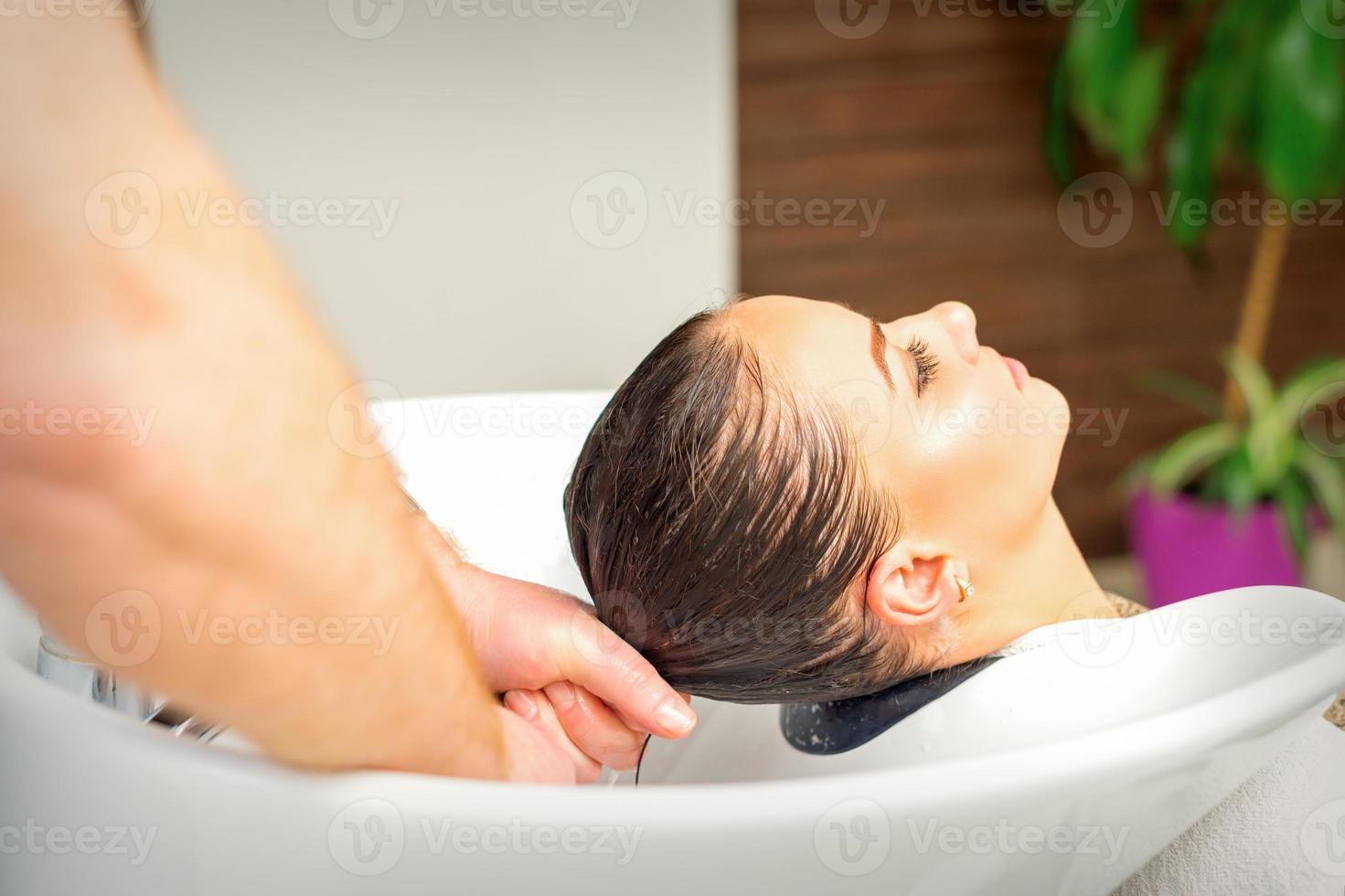 Hairdresser washing hair of client photo