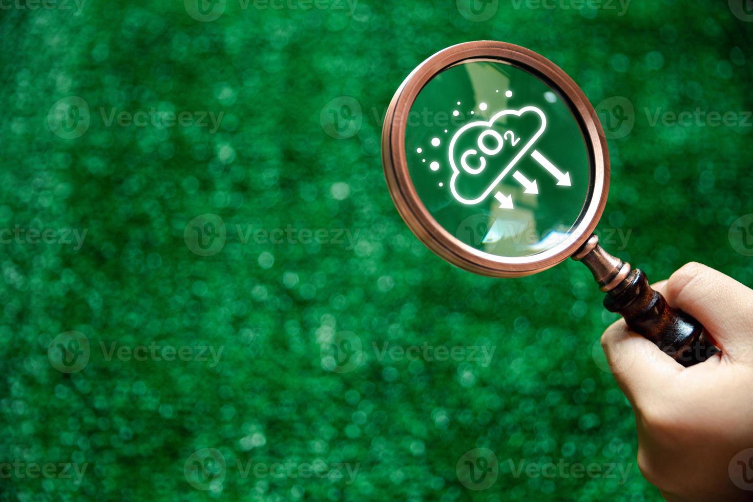 Carbon credit concept. CO2 reducing icon inside magnifier glass on green background, Tradable certificate to drive industry in direction of low emissions in efficiency cost. decrease CO2 photo