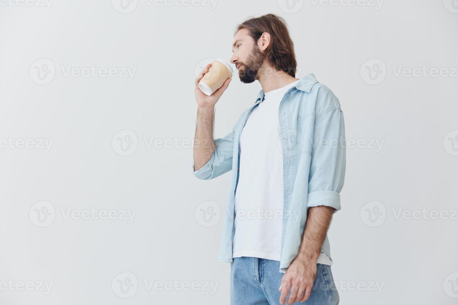 Lanza libre milenario hombre con barba Bebiendo café desde un cangrejo taza en elegante hipster ropa en un blanco antecedentes foto