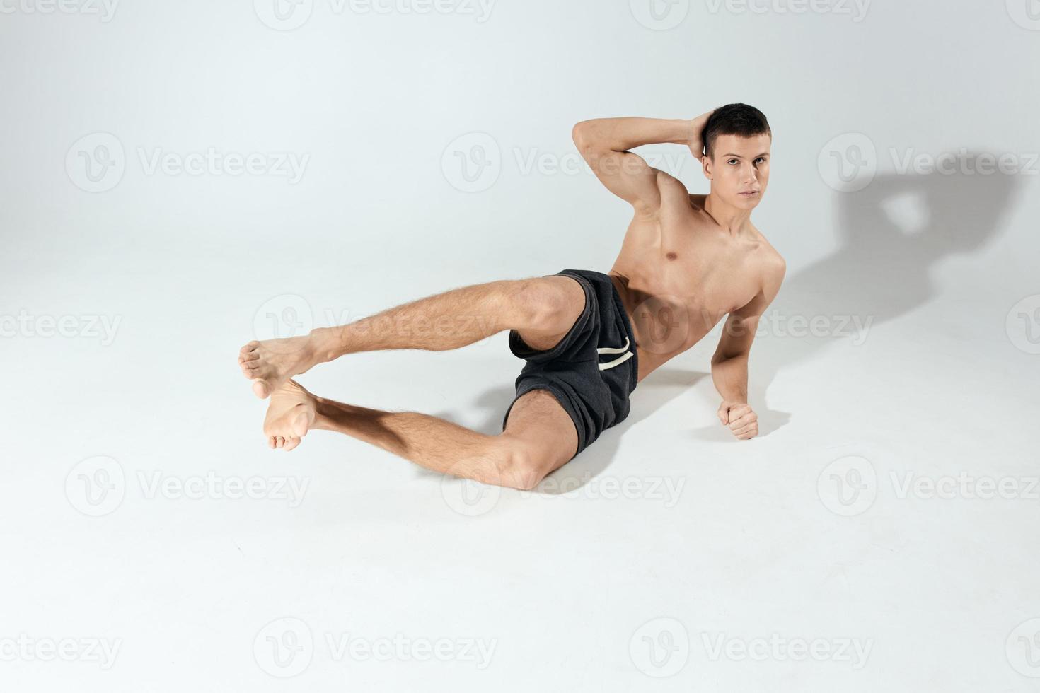 sports guy doing exercises in shorts in a bright room front view photo