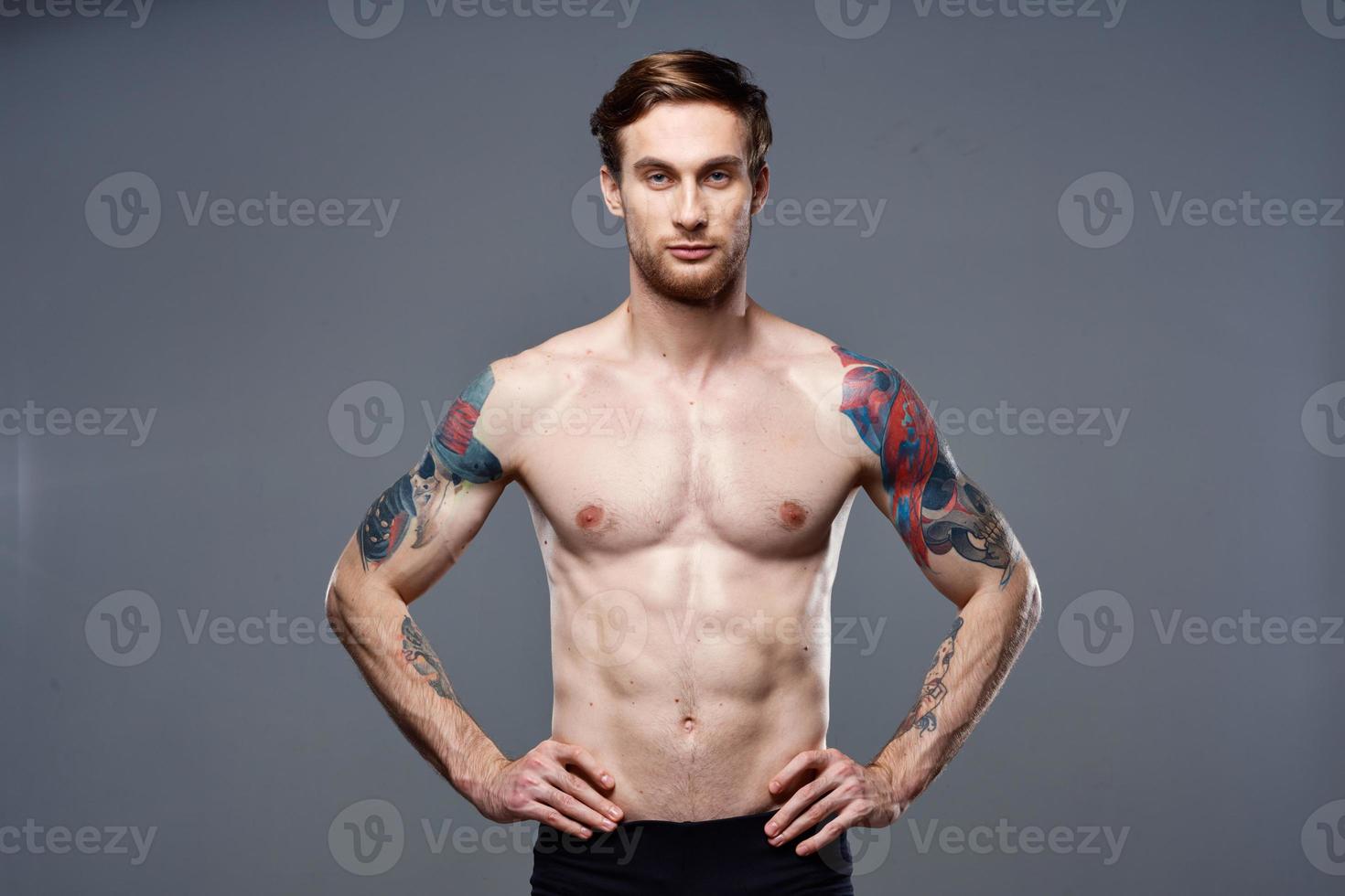 athletic man with pumped up abs tattoos on his arms photo