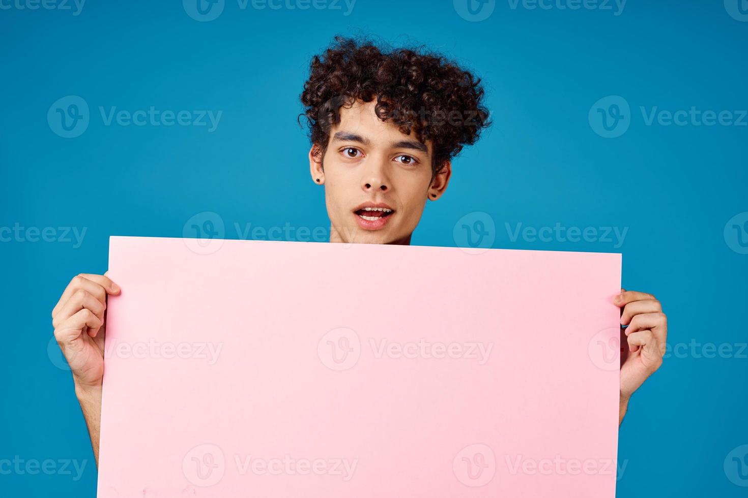 man with curly hair holding pink poster banner blue background photo