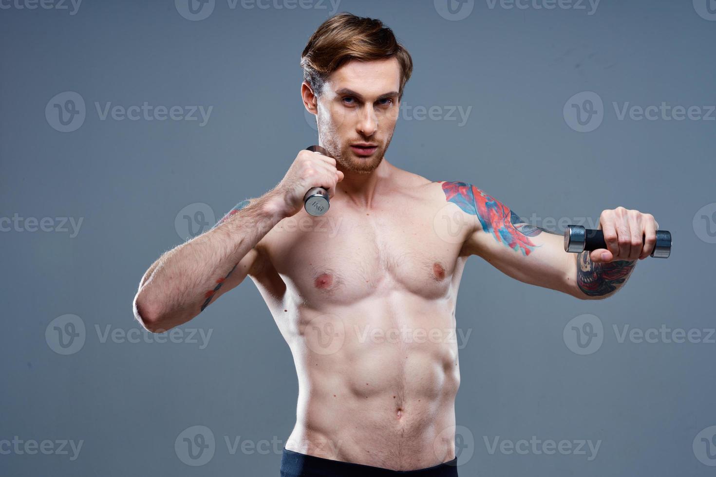 sexy athletic men with dumbbells on gray background and biceps press tattoos photo