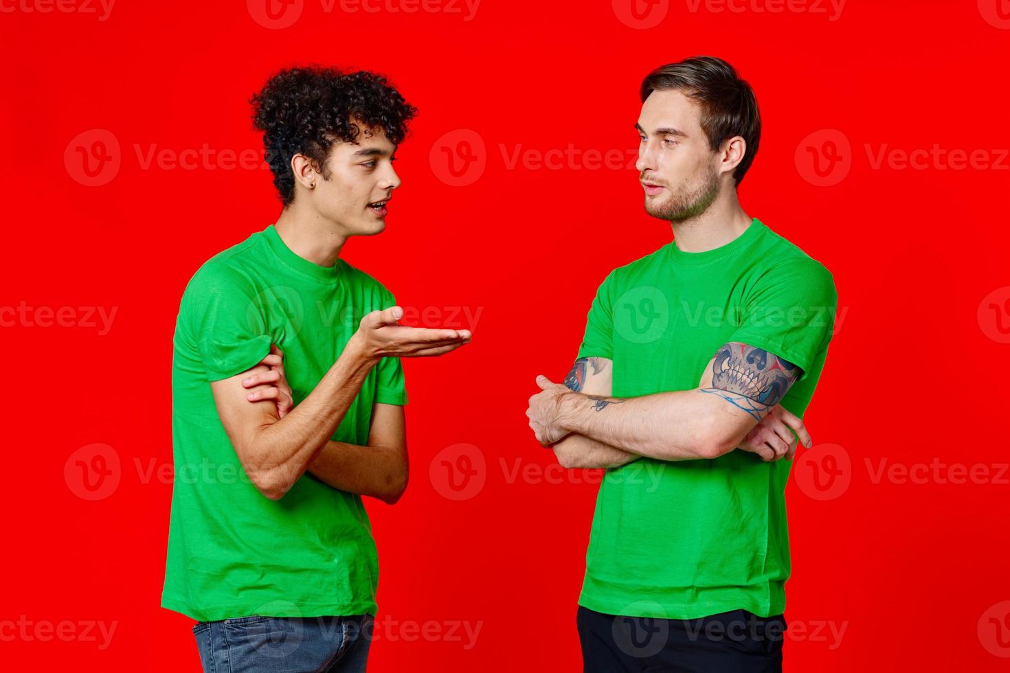 two friends in green t-shirts are standing side by side communication positive red background photo
