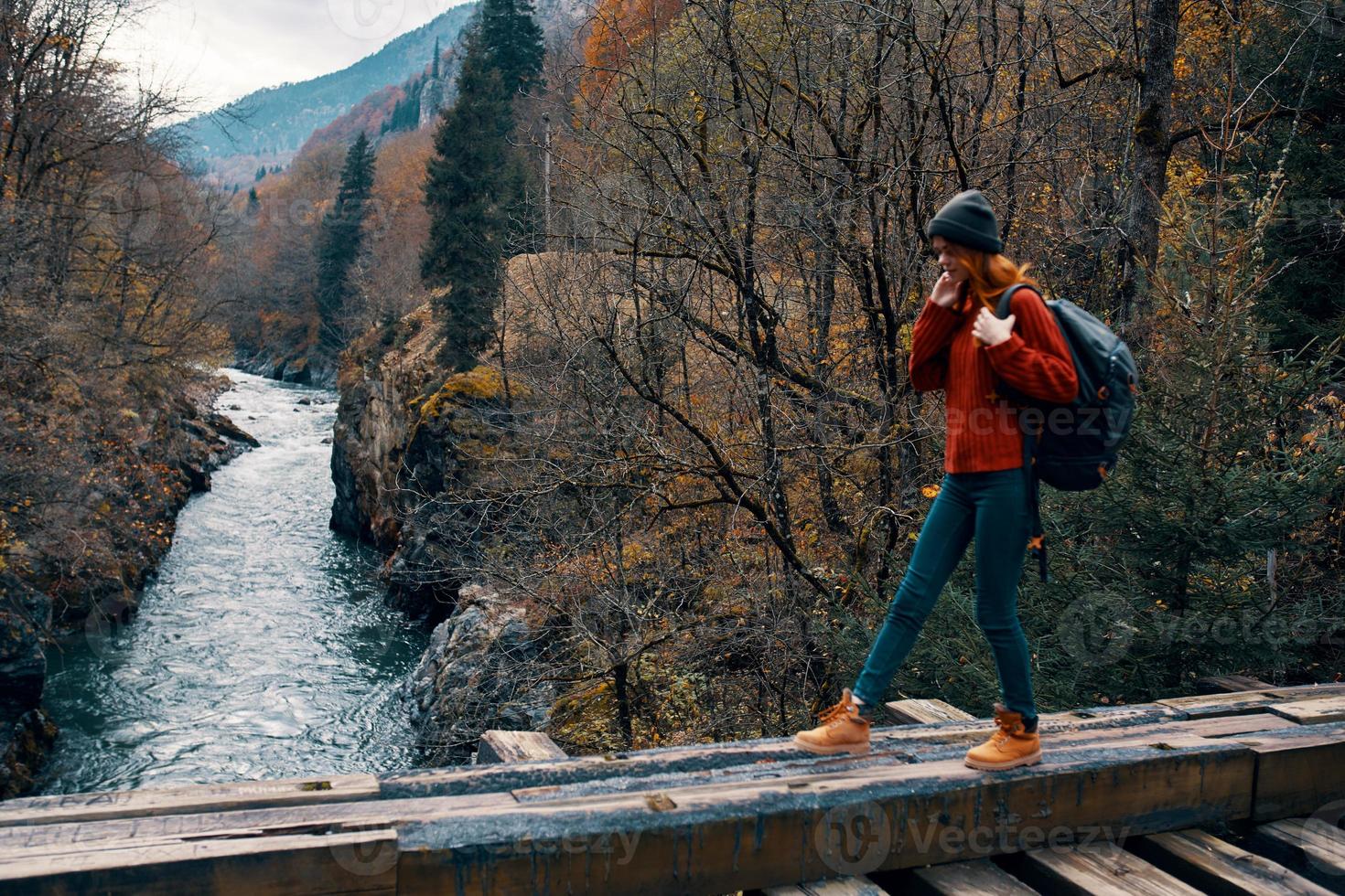 woman stands on a bridge over a river in the mountains Autumn forest travel photo