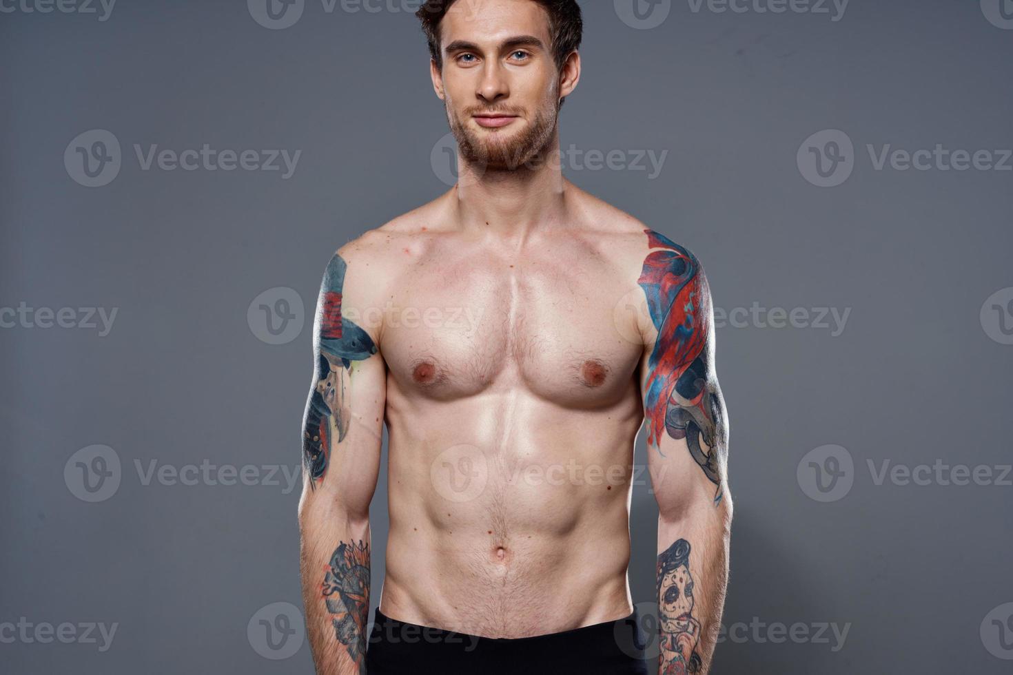 sporty man with a naked torso pumped up press tattoos on his arms photo