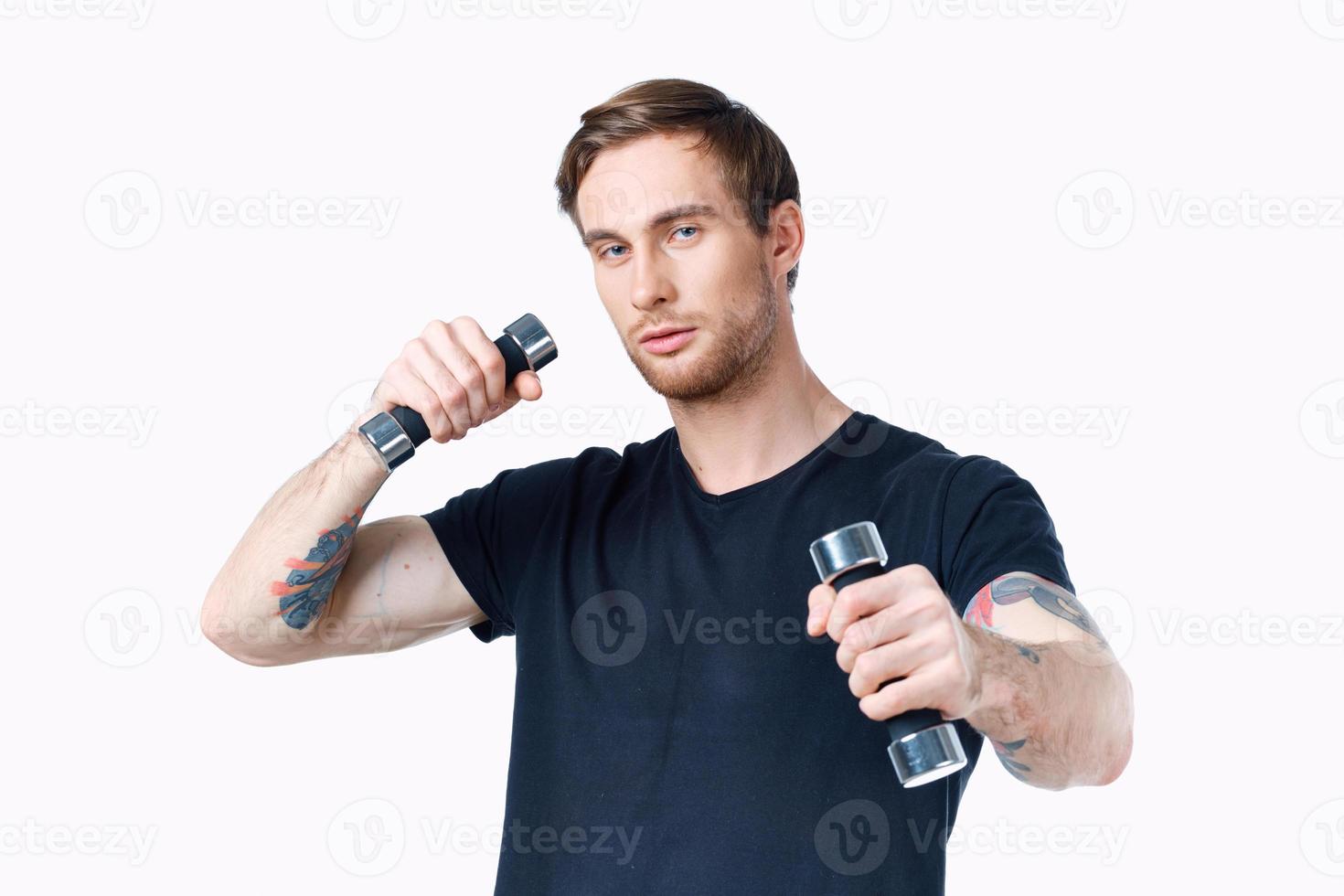 athlete with dumbbells in his hands on a white background in a black t-shirt photo