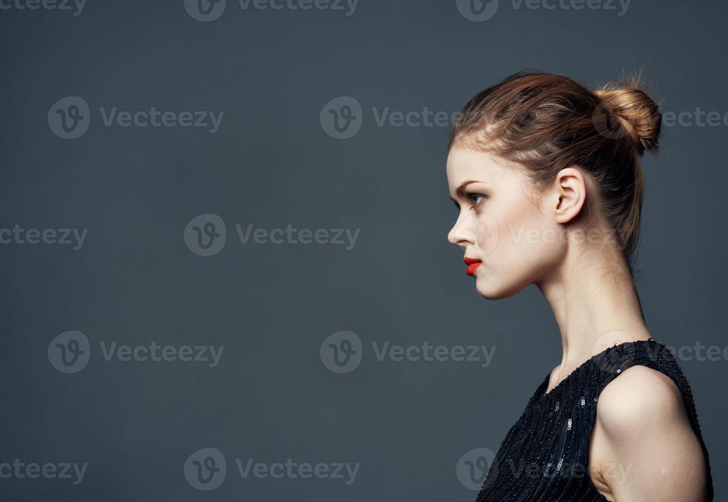 Side view of beautiful woman in black dress with hairstyle photo