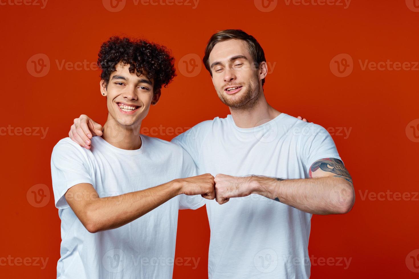 two friends in white t-shirts hugs communication red background photo