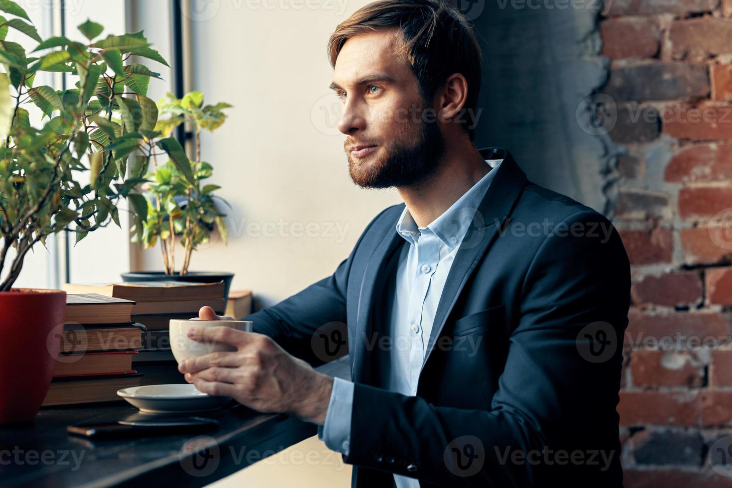a man in a suit sitting in a cafe with a cup of coffee leisure Professional photo