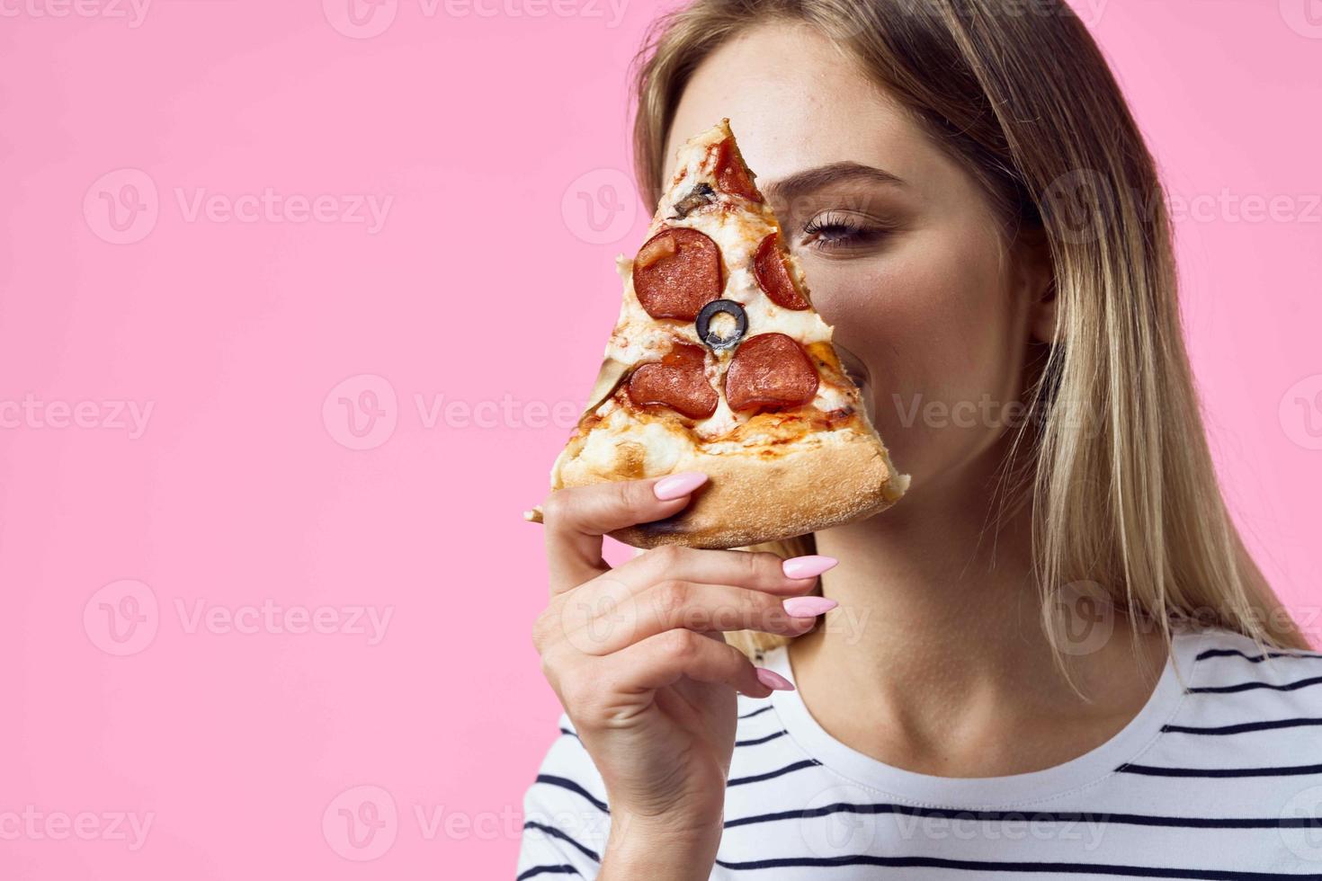 mujer en a rayas camiseta con Pizza en manos rápido comida bocadillo rosado antecedentes foto