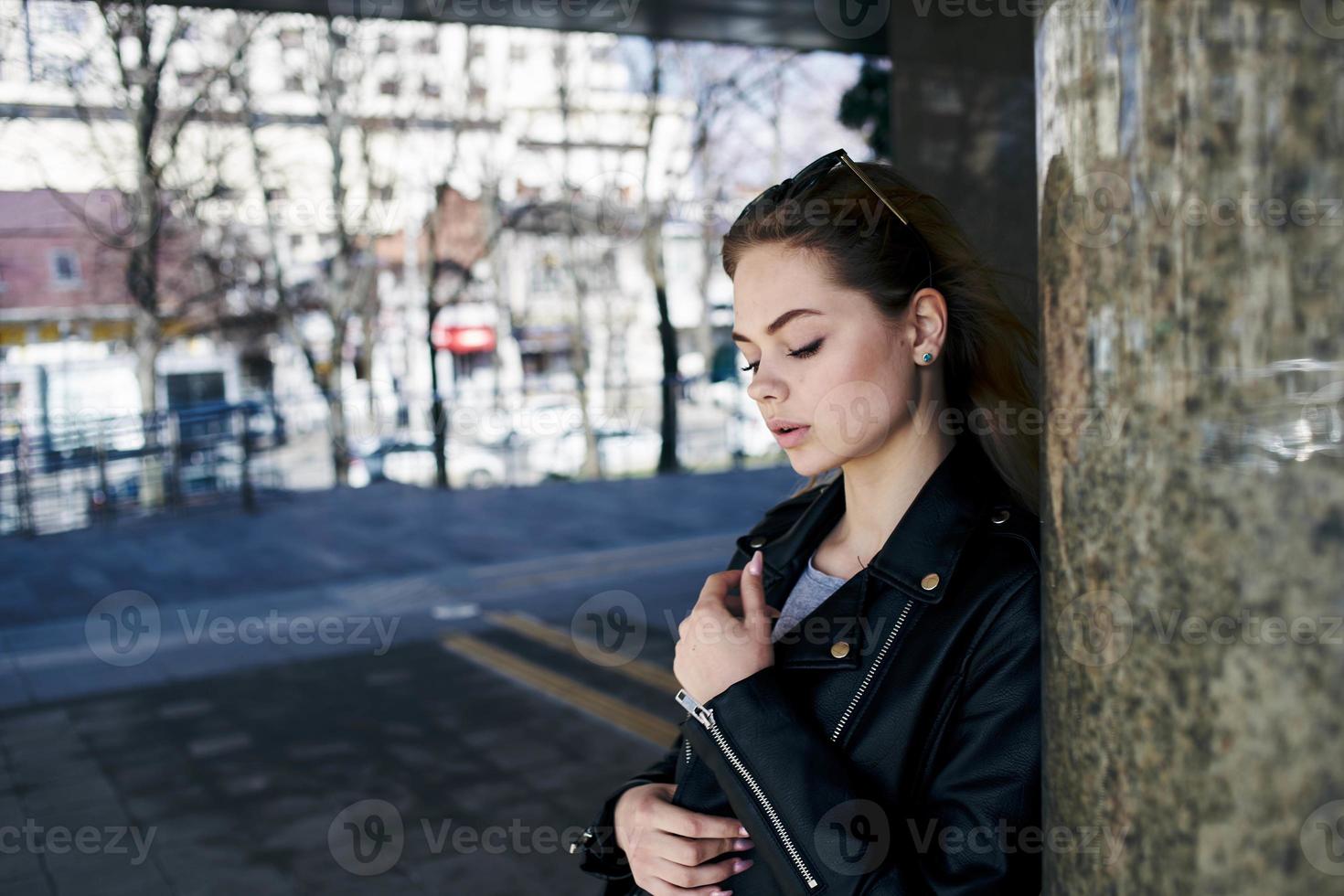 woman in leather jacket on the street in the city and edition sunglasses in the background photo