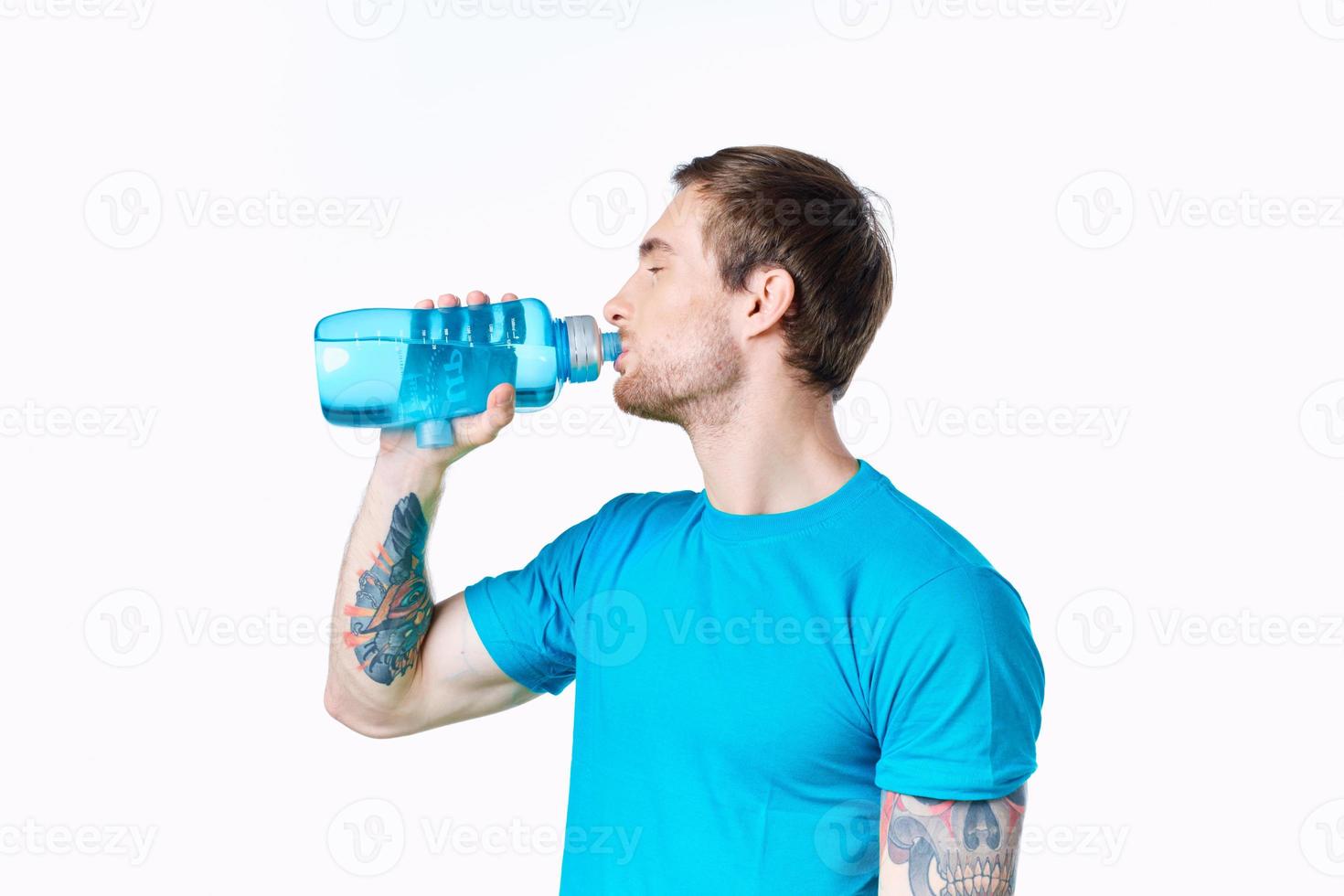 sexy athletes with a bottle of water and in a blue t-shirt on a white background drink photo