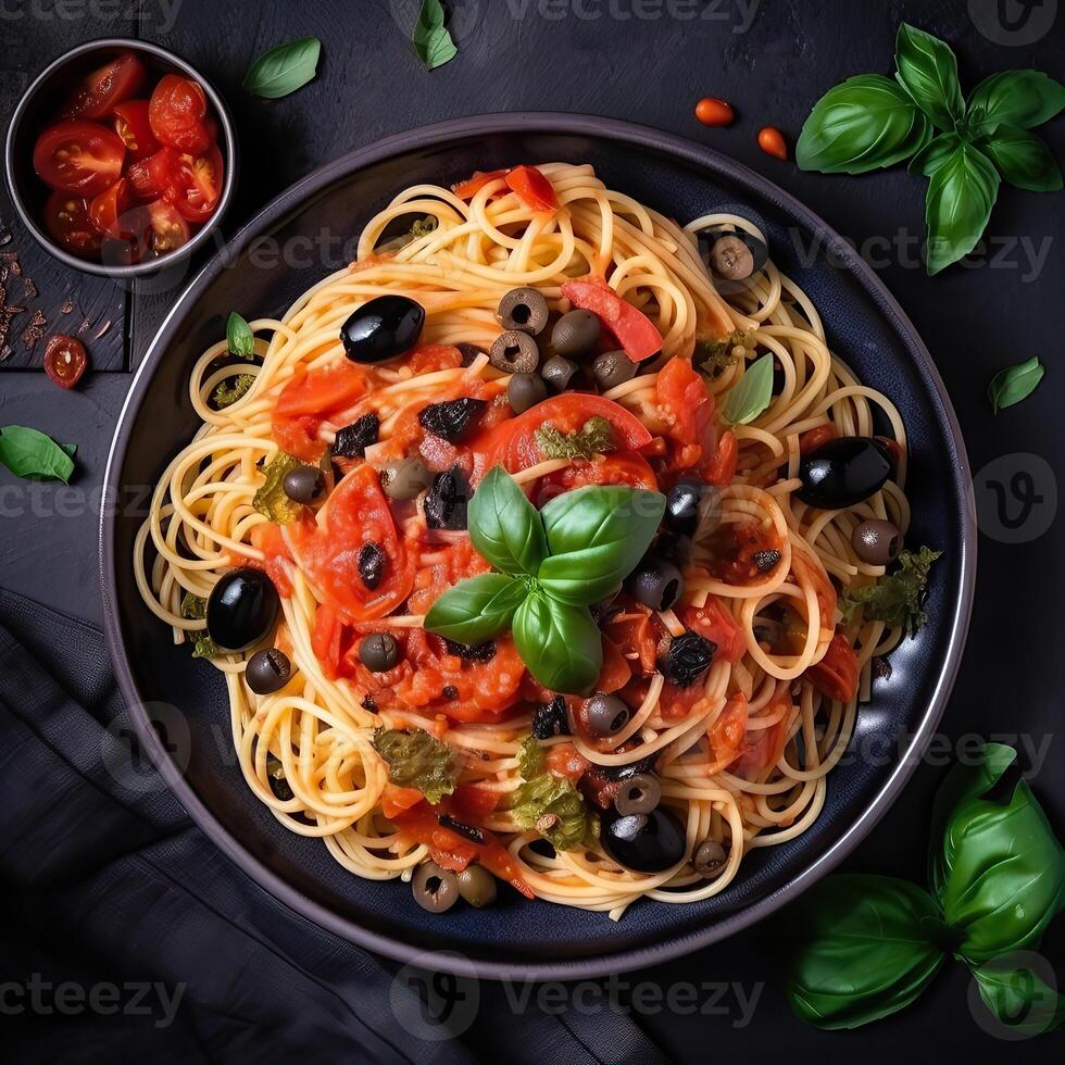 Spaghetti. Italian pasta dish with tomatoes, black olives, capers, anchovies and basil on dark table. Top view. . photo