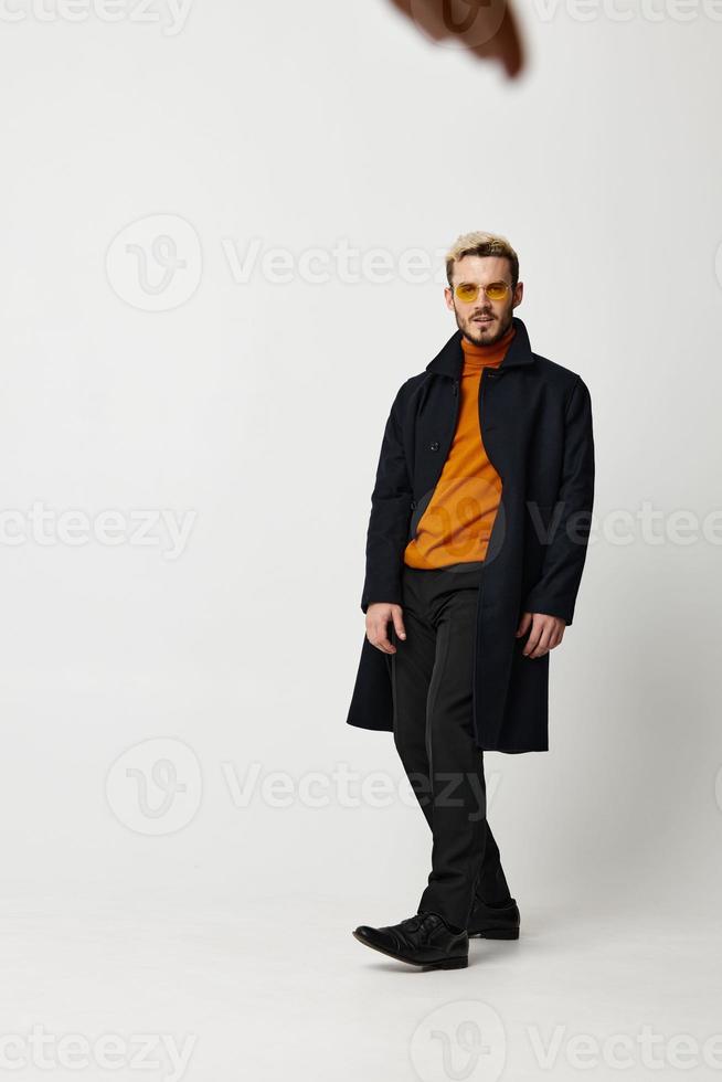 stylish man model in coat sweater and pants boots light background photo