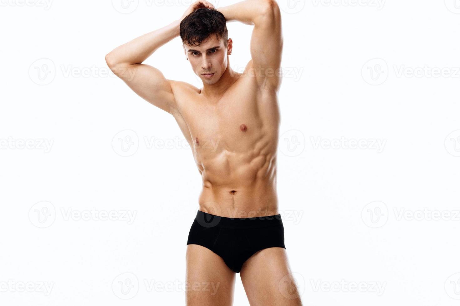 attractive sportsman with a pumped-up torso holds his arms above his head photo