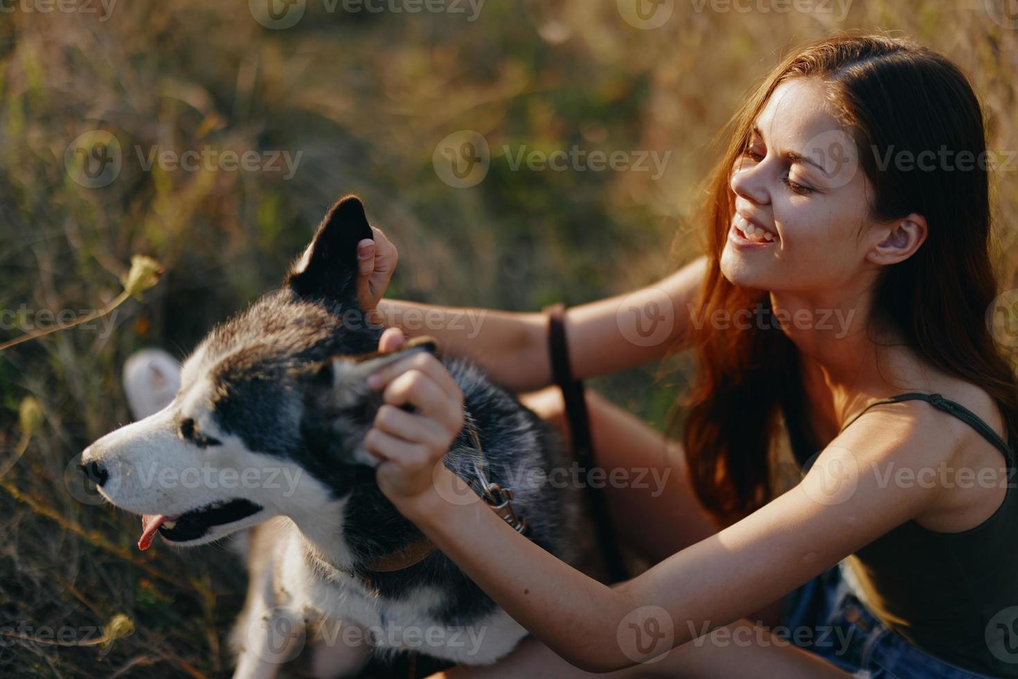 Woman sitting in field with dachshund dog smiling while spending time outdoors with dog friend photo