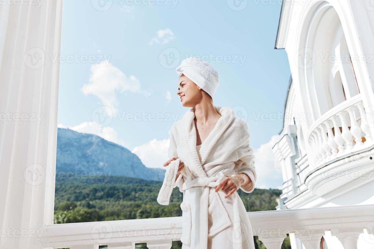 Attractive young woman with a towel on my head in a white bathrobe staying on the balcony in a hotel Mountain View photo