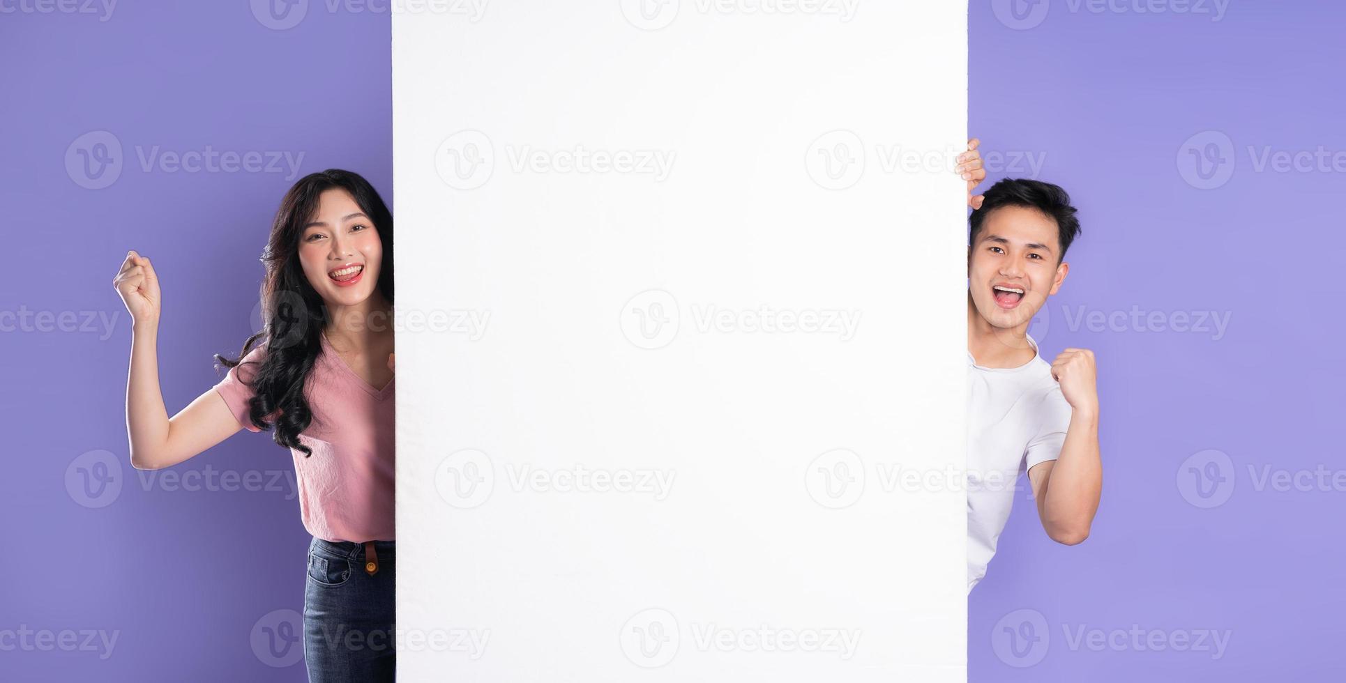 image of asian couple posing next to billboard, isolated on purple background photo