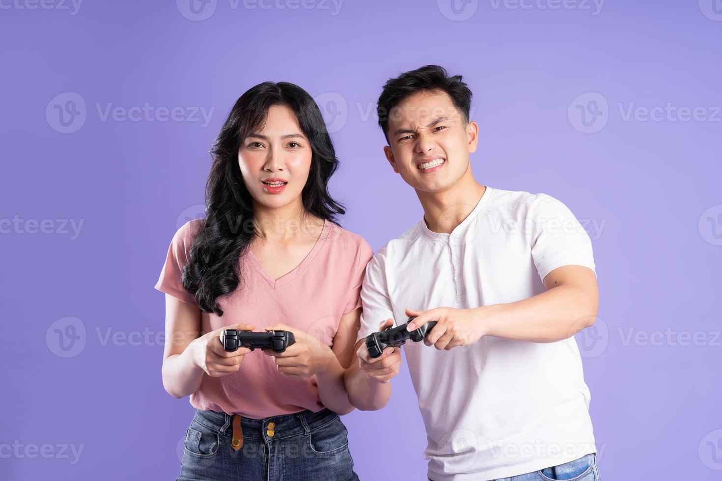 image of asian couple playing games, isolated on purple background photo