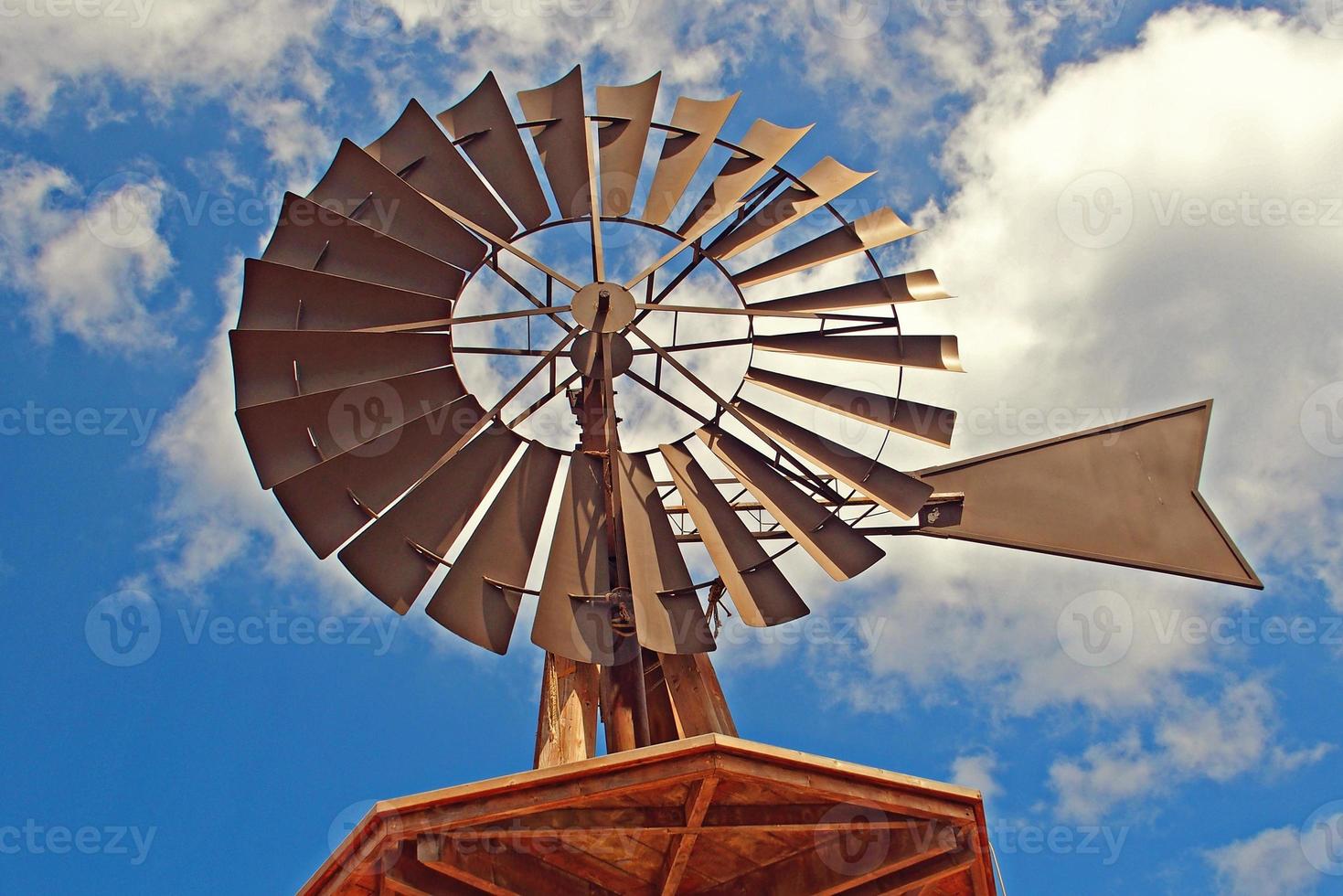 American windmill into the water against a blue sky with white clouds photo