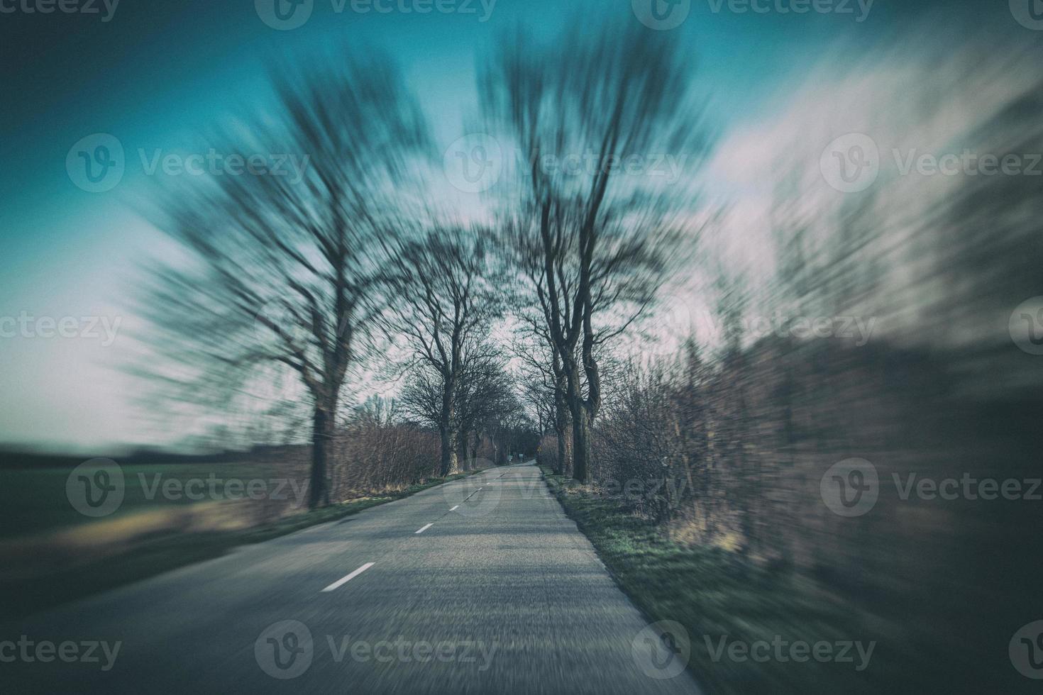 old narrow asphalt road with trees on the side of the road during a car ride in early spring photo