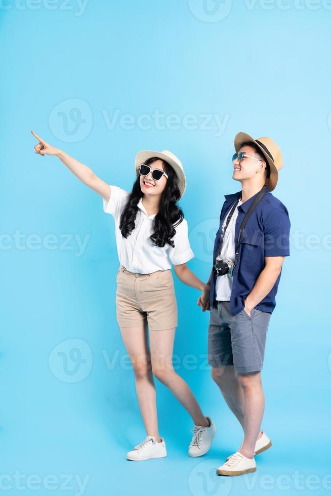 Asian couple traveling image  isolated on blue background photo