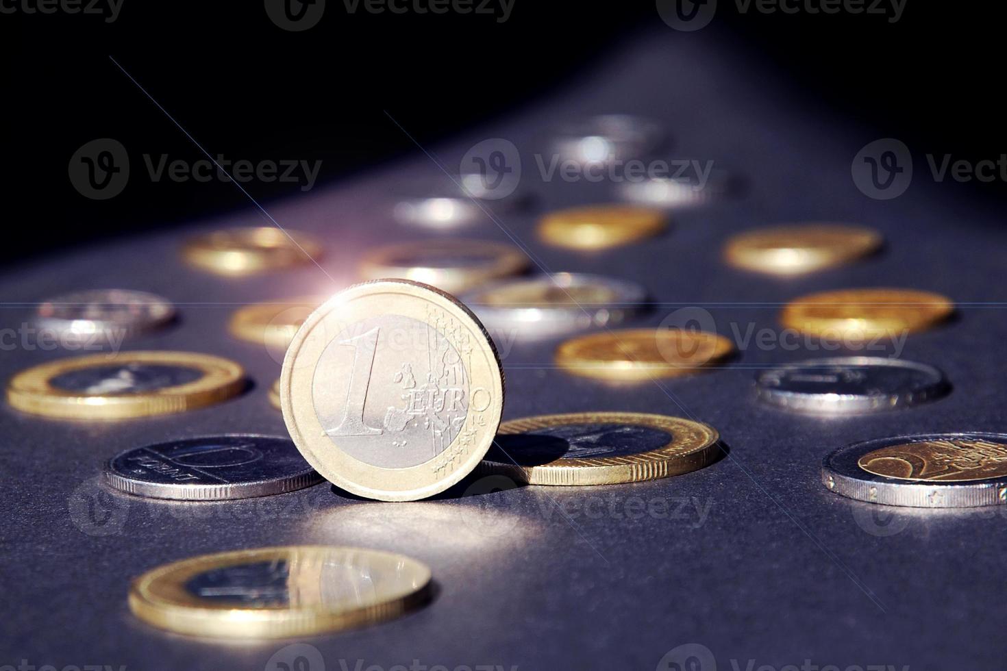 uno euro moneda en pie en borde brillante en destacar en contra muchos diferente monedas en oscuro antecedentes. dinero fluir foto