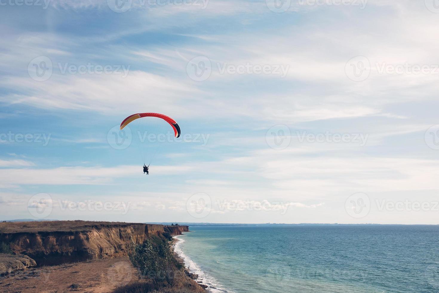 paragliders tandem in blue sky over the sea shore photo