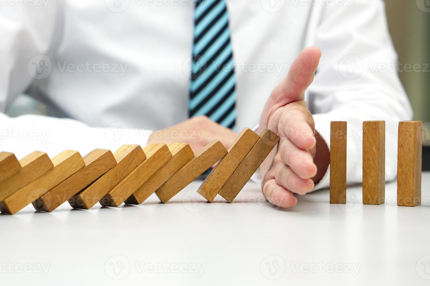 Hand prevent wooden block falling domino effect from continuous fall. Risk management, strategic, insurance and business plan concept. photo