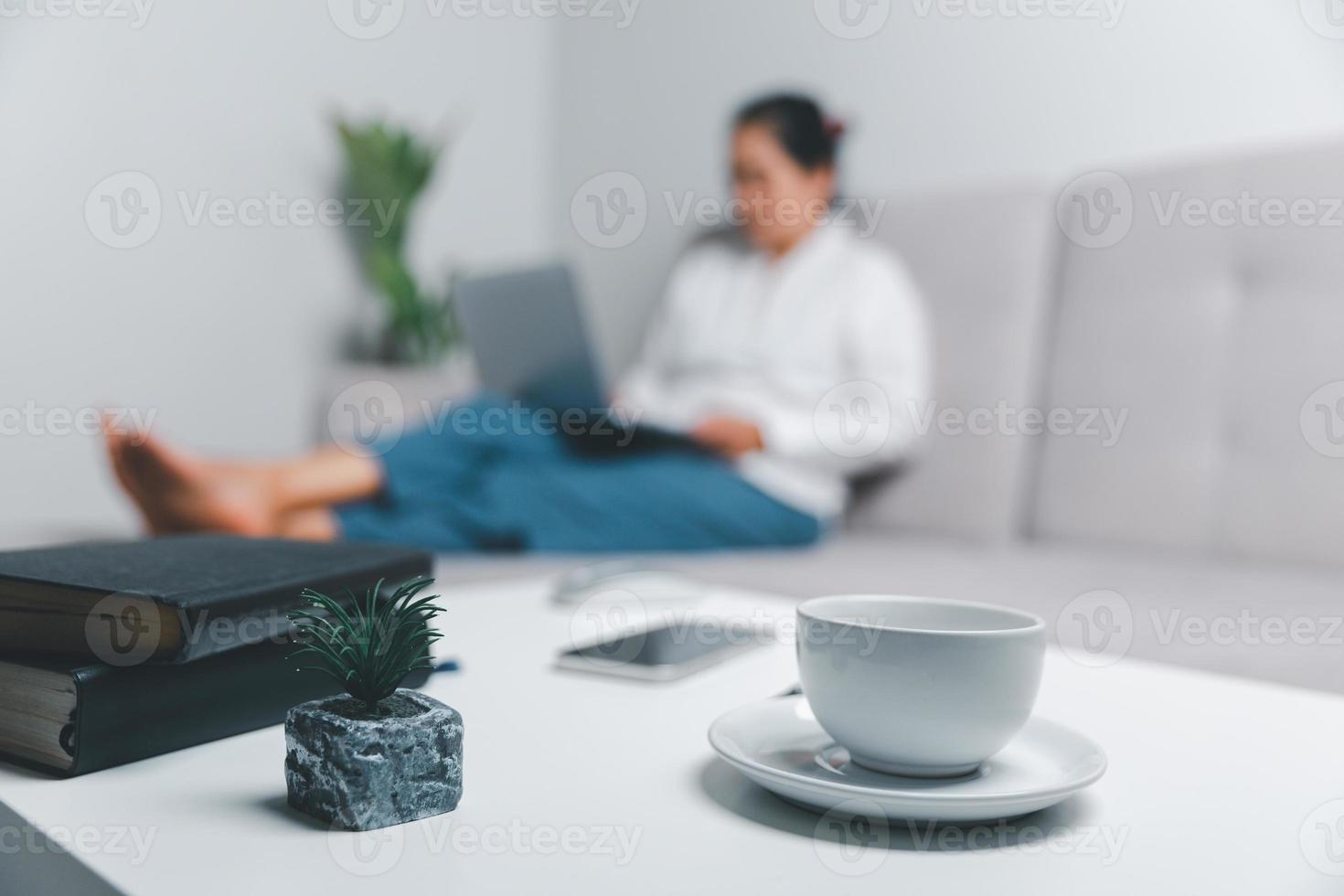 Social media day concept. Female freelancer starting working day early in morning drinking coffee in living room for website with using modern laptop computer. Businesswoman working in home office. photo