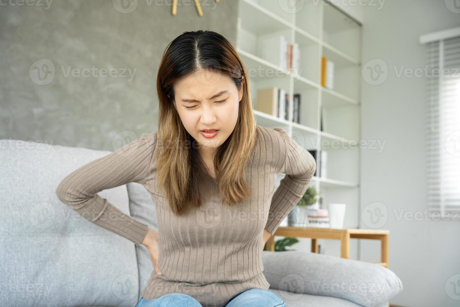 Asia beautiful woman holding her lower back while and suffering from unbearable pain health and problems, chronic back pain, backache in office syndrome, scoliosis, herniated disc, muscle inflammation photo