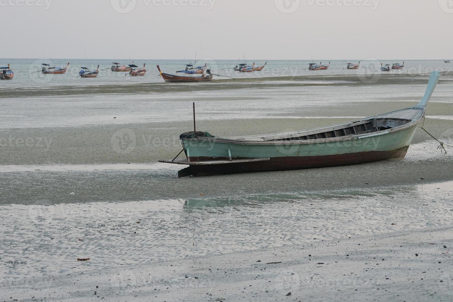 Group of traditional long tail boat floating in the sea with seascape and clear sky in background photo