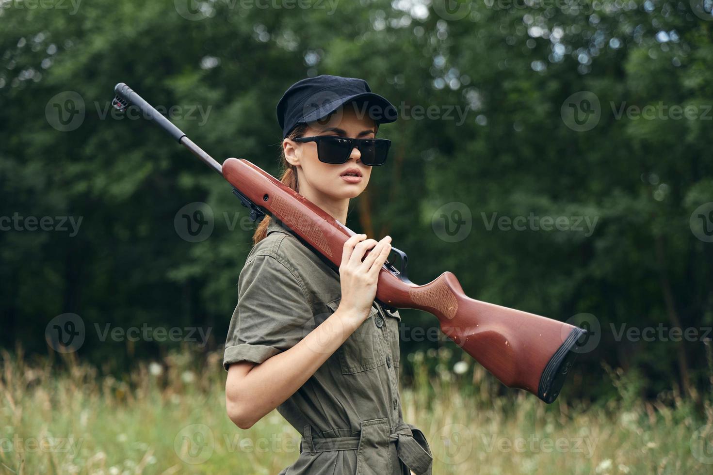 mujer en al aire libre participación un arma en su hombro Gafas de sol verde mono foto