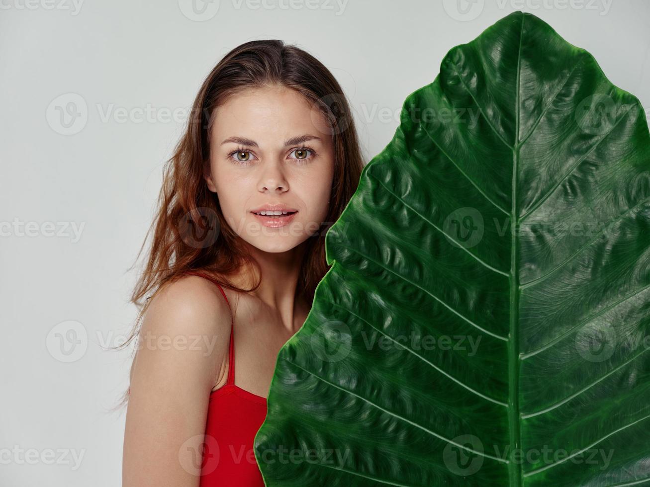 happy woman in a red t-shirt near a palm leaf smiles photo