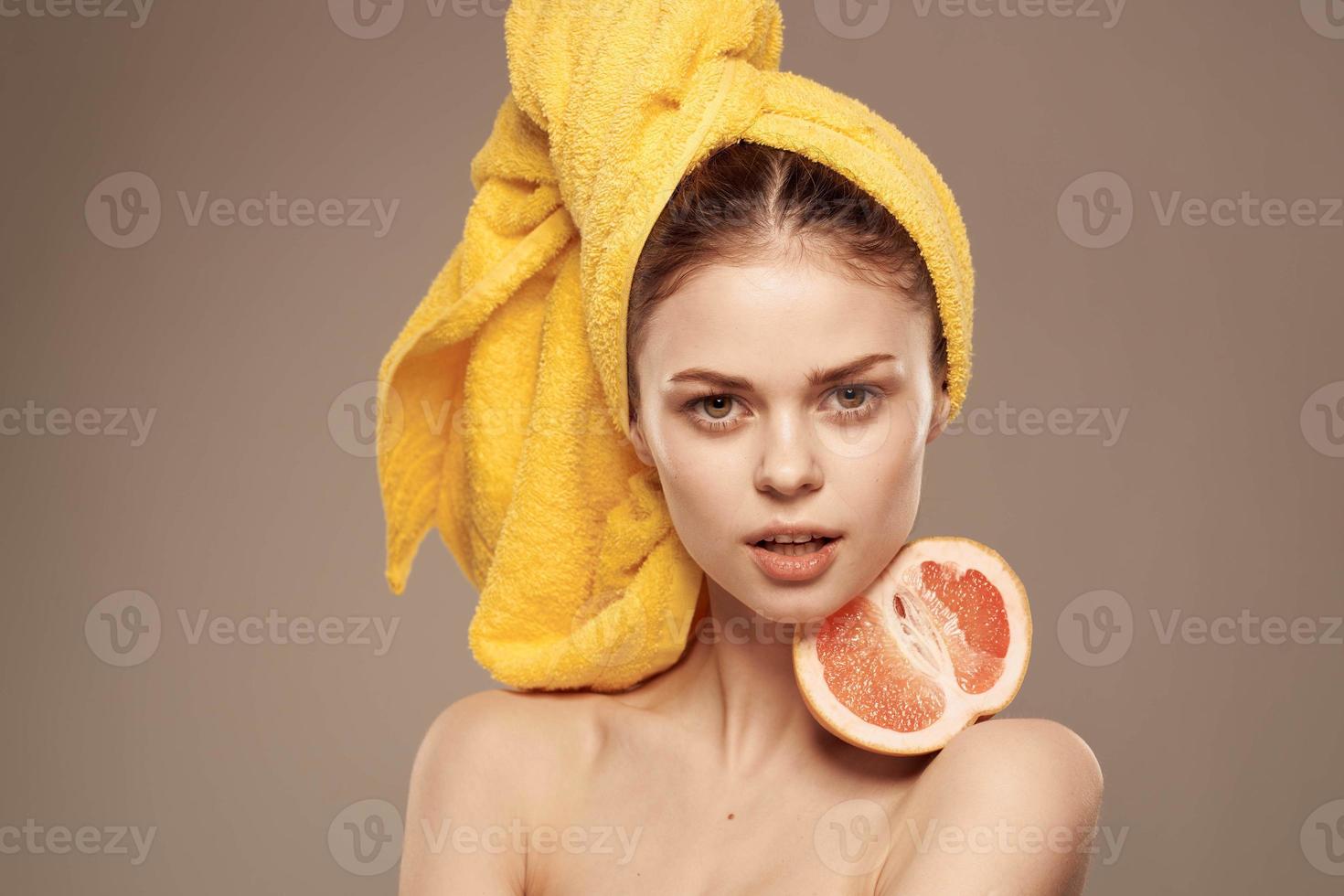 mujer con desnudo espalda amarillo toalla en su cabeza pomelo en manos limpiar piel cuidado foto