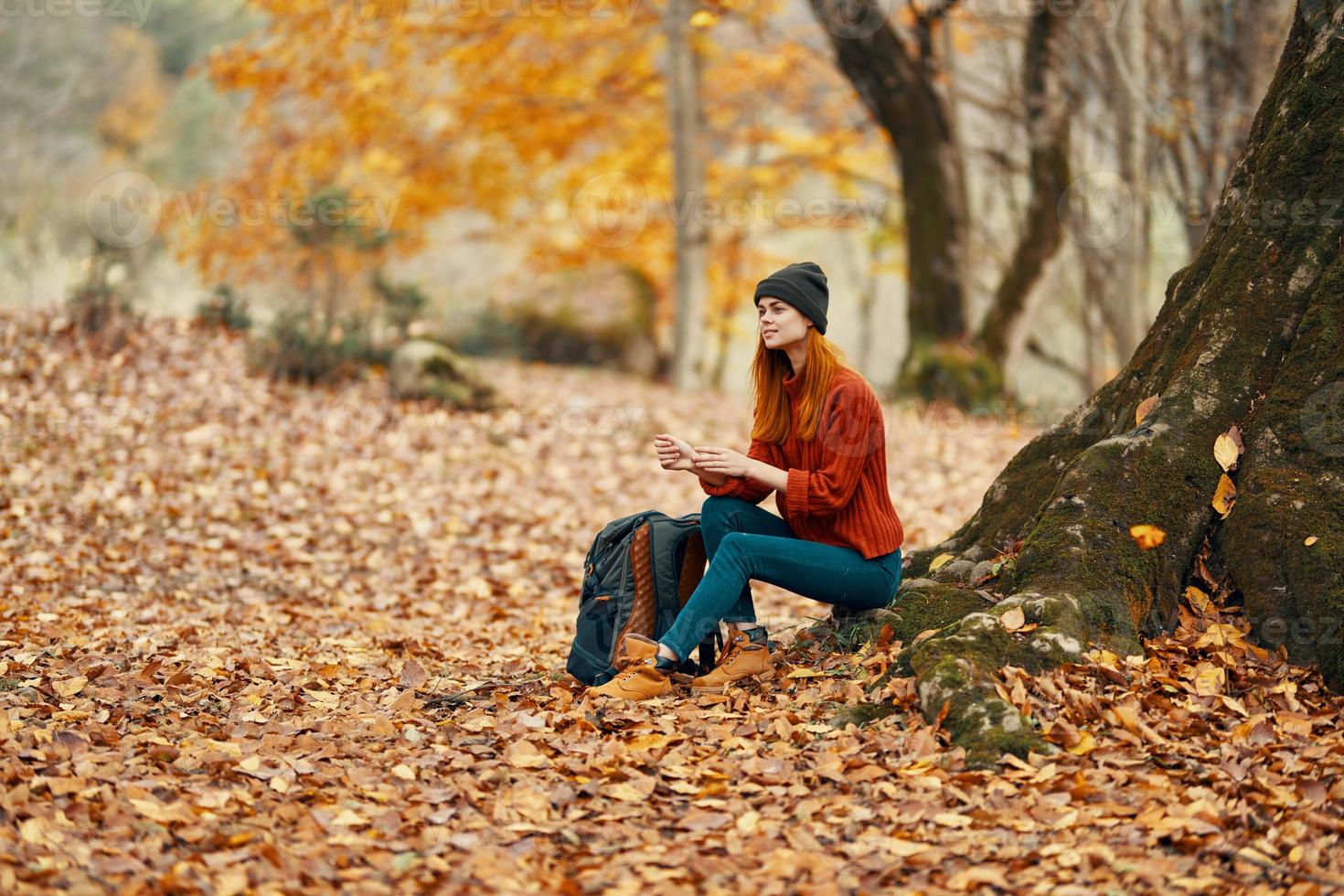 mujer sentado cerca un árbol en otoño bosque y que cae hojas paisaje parque foto