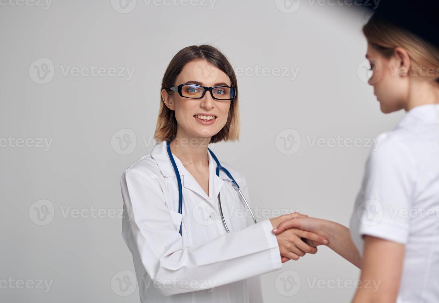 doctor and patient shaking hands on a light background stethoscope around the neck photo