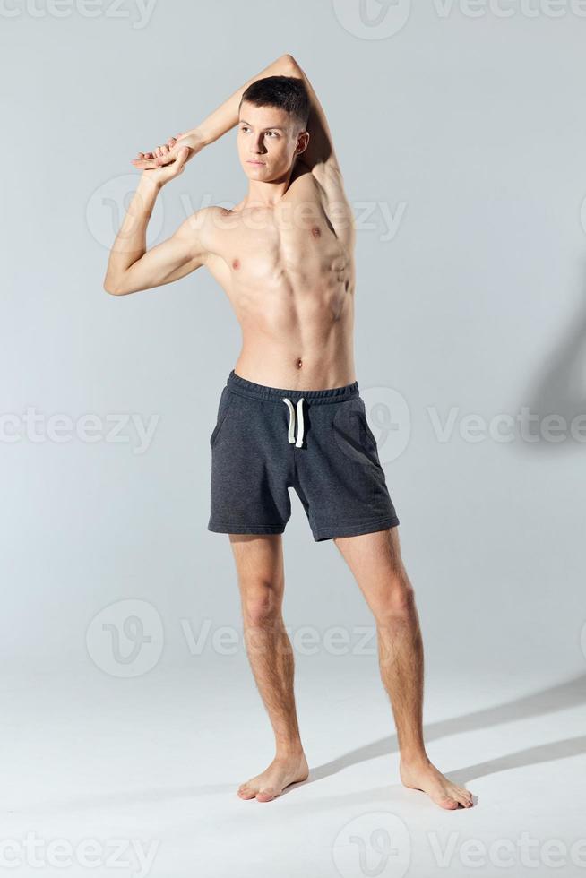 athlete in shorts with a naked torso joined hands behind the head photo