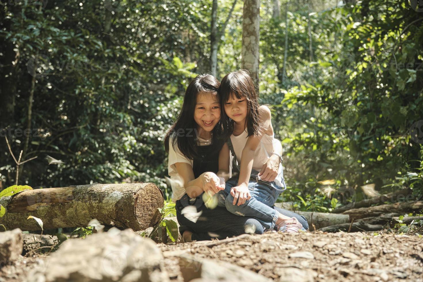 Asian mum and girl cheerful with many swarms of butterflies flying, beautiful wings, eating food on salt marshes in tropical forests of National Parks, outdoor learning experience, nature knowledge. photo