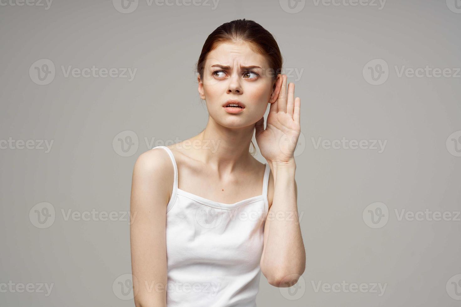 sick woman poor hearing disorders in white t-shirts light background photo