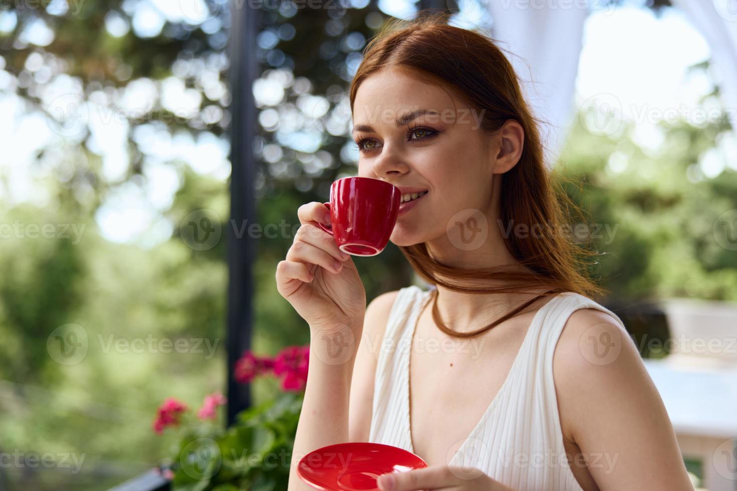 Portrait of young beautiful woman with red cup of coffee outdoors cafe Summer day photo