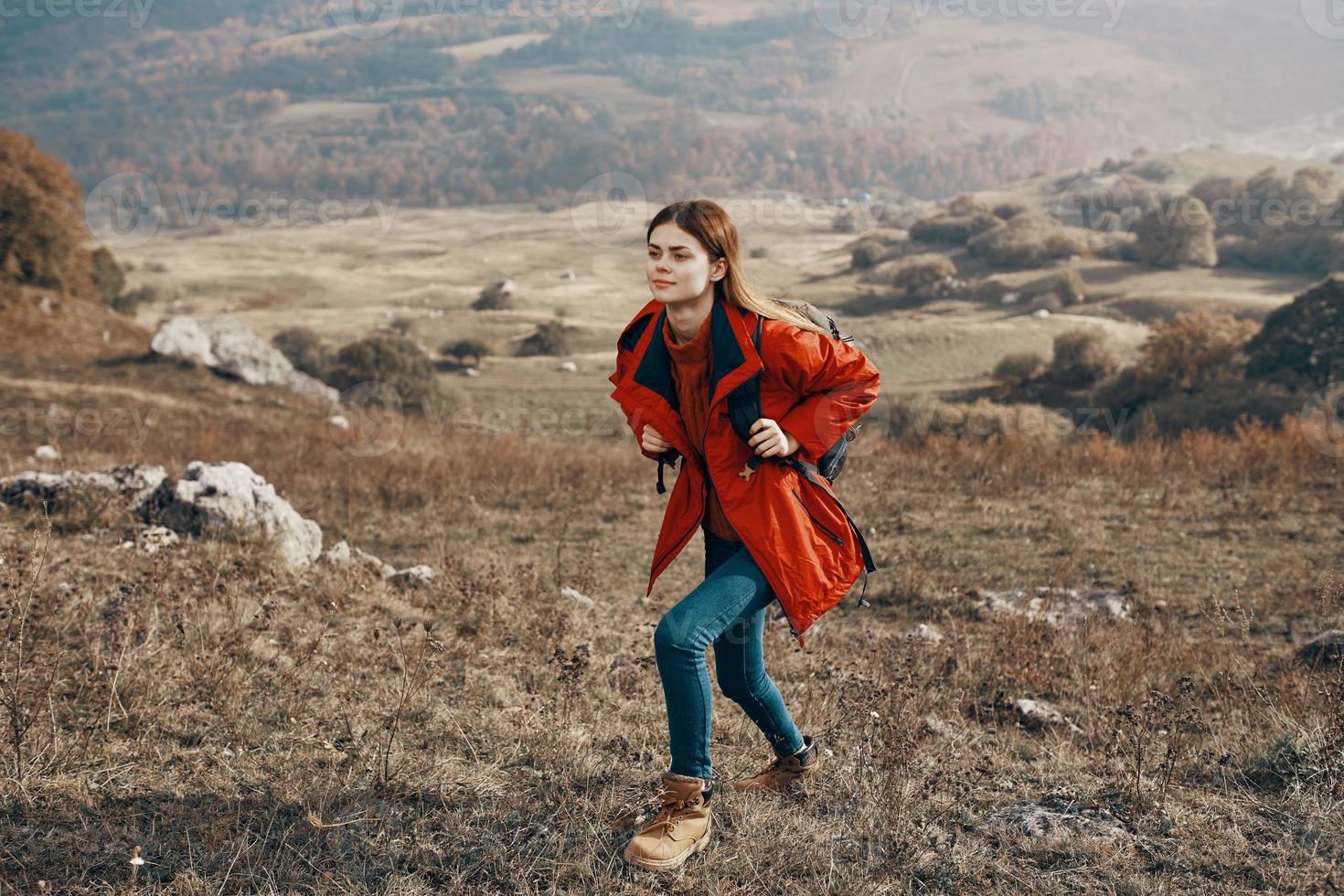 young woman hiker traveling in the mountains on nature and landscape backpack jacket jeans boots photo