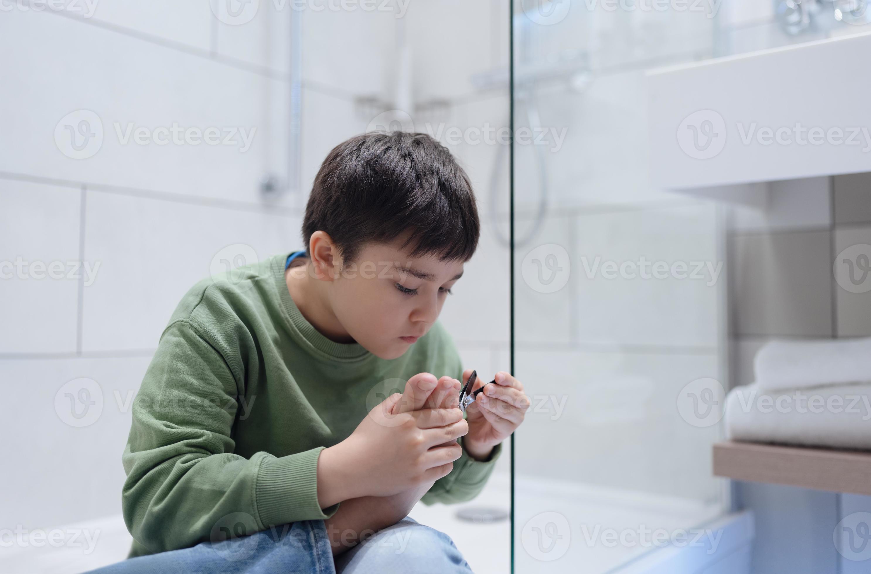 Portrait Kid clipping nails in the bathroom, Child boy Cutting toe nails with nail clippers