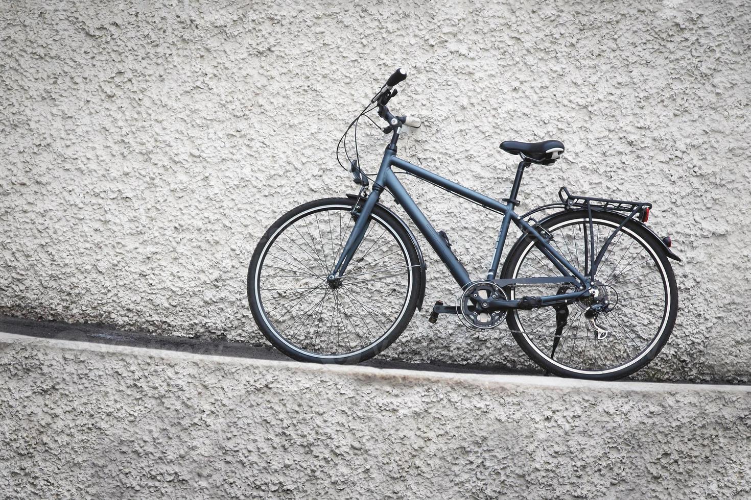 Bicycle parked against grungy stone wall photo