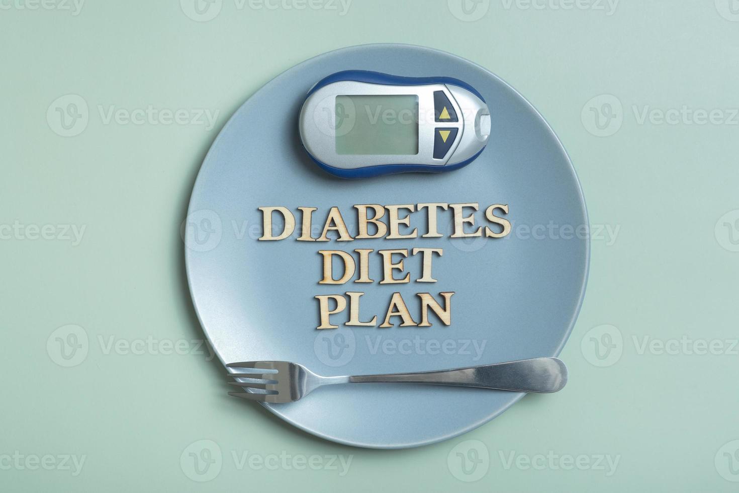 Diabetes Diet Plan text. Glucometer and plate on colored background photo